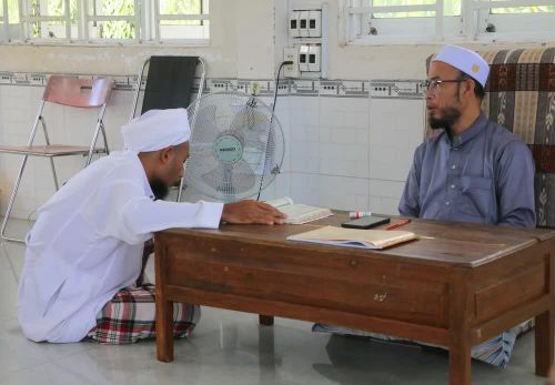 Học sinh người dân tộc Chăm ở cấp độ số 4 (đọc thuộc, đúng âm điệu Kinh Al-Qur’an và giáo lý Islam nâng cao) đang trả bài tập với thầy giáo sau mỗi tuần học