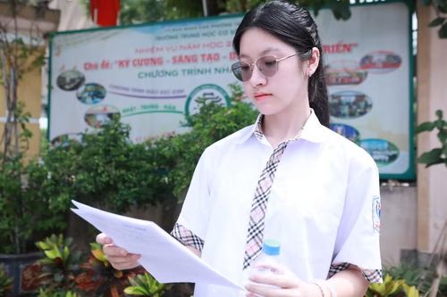 Thảo Vy xem lại đề Tiếng Anh và Lịch sử sau buổi thi cuối cùng sáng 12/6. Ảnh: Đình Tuệ.
