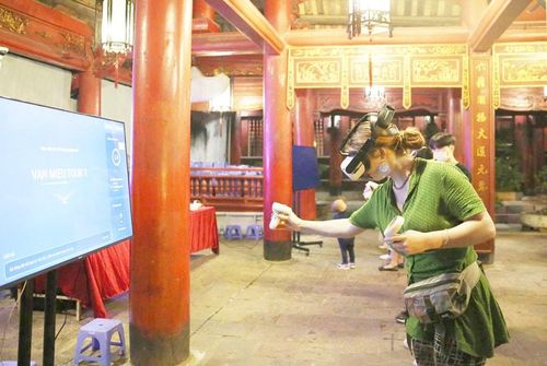 Du khách trải nghiệm công nghệ điều khiển chuyển động 3D để khám phá nội dung các cuốn sách tại Khu di tích Văn Miếu - Quốc Tử Giám. Ảnh: Nhật Nam