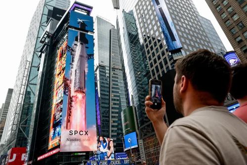 Một người đàn ông đang chụp ảnh quảng cáo của SpaceX vào ngày công ty này thực hiện IPO tại Nasdaq MarketSite ở thành phố New York, hôm thứ Sáu. Ảnh: Reuters.