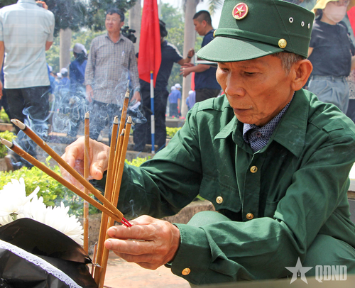 Cựu chiến binh thắp hương lên mộ đồng đội trong ngày các anh được trở về yên nghỉ vĩnh hằng.