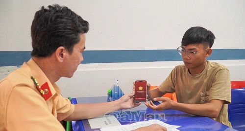 Cán bộ Phòng CSGT (Công an tỉnh Cà Mau) hướng dẫn người dân tích hợp giấy đăng ký xe trên VNeID.