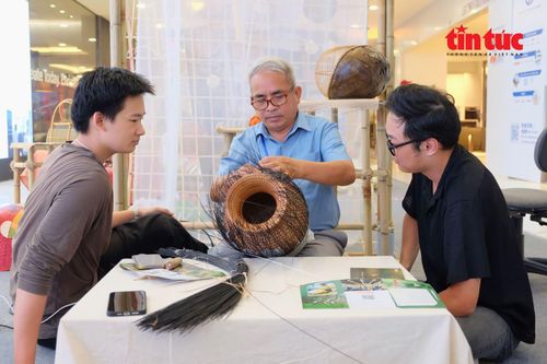 Nghệ nhân Nhân dân Nguyễn Văn Tĩnh hướng dẫn hai bạn trẻ cách làm sản phẩm mây tre đan.