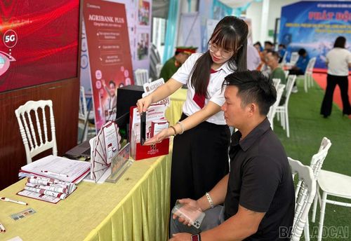 Nhân viên ngân hàng hỗ trợ khách hàng cài đặt ứng dụng.