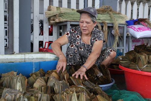 Mỗi người chia nhau làm các công đoạn như: ngâm nếp, chẻ lạt, xếp lá, gói bánh… Ảnh: KHÁNH NGÂN