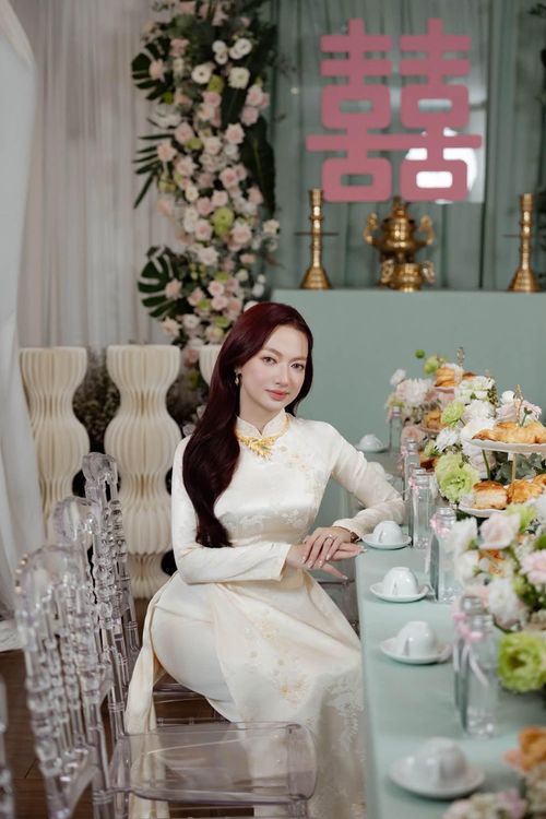  Trong lễ ăn hỏi, Xuân Nghi diện áo dài truyền thống, trang điểm nhẹ nhàng. Cô để kiểu tóc buông xõa, kết hợp thêm một số phụ kiện là trang sức. Không gian lễ ăn hỏi được trang hoàng tinh tế với hai tông màu xanh và hồng. 