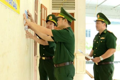 Cán bộ Biên phòng dán tờ rơi được in mã QR tại nhà văn hóa bản Phá Lõm.
