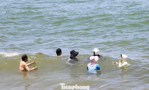 Một nhóm người đội mũ, mặc đồ che kín để tránh nắng để tắm biển ngày Tết Đoan Ngọ