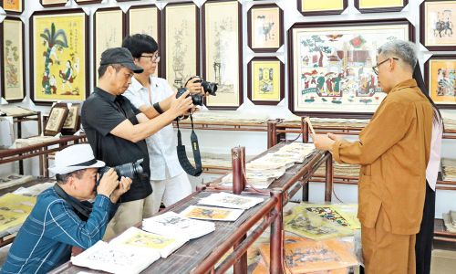 Các nghệ sĩ nhiếp ảnh, phóng viên tác nghiệp tại không gian trưng bày tranh dân gian Đông Hồ của gia đình nghệ nhân Nguyễn Đăng Chế. 