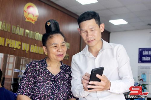 Cán bộ Trung tâm Phục vụ hành chính công phường Chiềng Sinh hướng dẫn người cao tuổi tra cứu hồ sơ điện tử trên điện thoại di động.