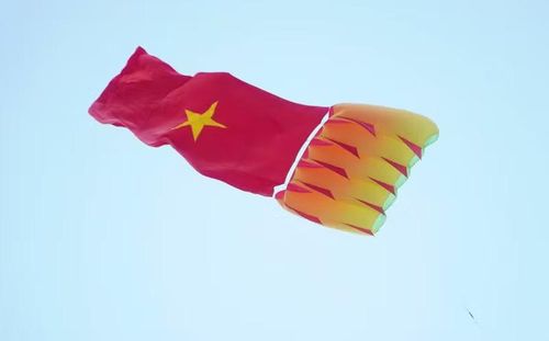 Cánh diều mang theo lá cờ đỏ sao vàng tung bay trên bầu trời.