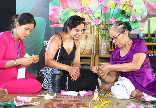 Khách nước ngoài chăm chú xem hướng dẫn làm hoa sen giấy Thanh Tiên