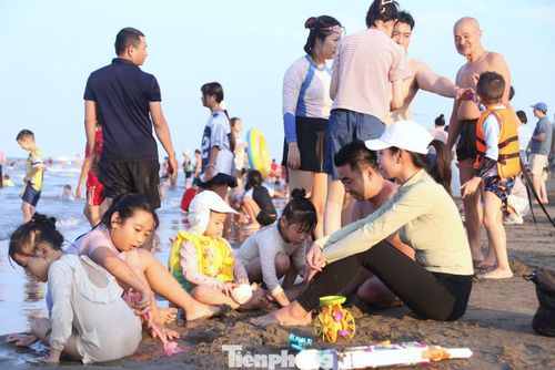 Trên bãi cát, trẻ em thích thú vui đùa cùng bố mẹ.
