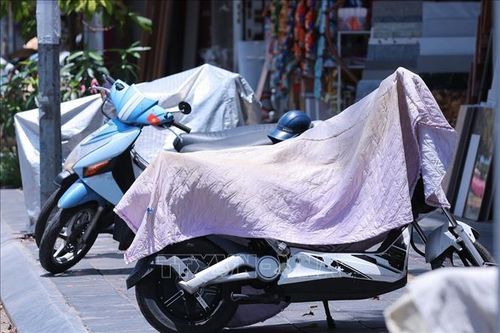 Nhiều chủ xe che chắn xe máy khi nhiệt độ ngoài trời của Hà Nội vượt ngưỡng 40 độ C.