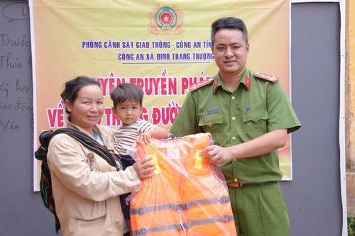 Công an xã Đinh Trang Thượng trao tặng áo phao cứu sinh cho người dân. Ảnh Lê Tiến