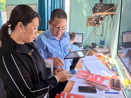 Cán bộ Ban quản lý Cảng cá Quy Nhơn hỗ trợ chủ tàu cá thao tác sử dụng nhật ký điện tử vào sáng 20-6. Ảnh: N.T