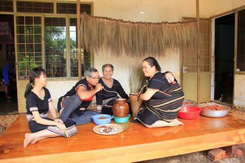 Một gia đình Tây Nguyên quây quần bên nhau thưởng thức các món ăn truyền thống và uống rượu cần. Ảnh tư liệu: Hồng Điệp/TTXVN
