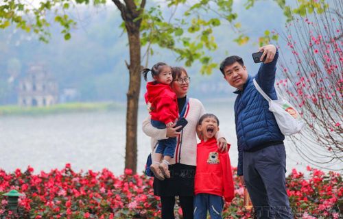Cả gia đình cùng nhau ghi lại khoảnh khắc của mùa Xuân bên hồ Gươm. Ảnh tư liệu: Thanh Tùng/TTXVN