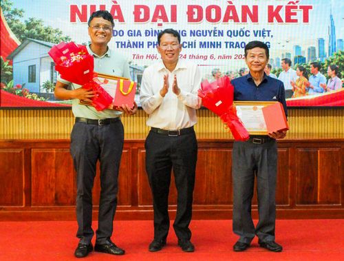 Chủ tịch UBND xã Tân Hội Nguyễn Minh Ngọc tặng giấy khen và hoa cho đại diện gia đình ông Nguyễn Quốc Việt (bìa trái) và ông Huỳnh Công Tấn.