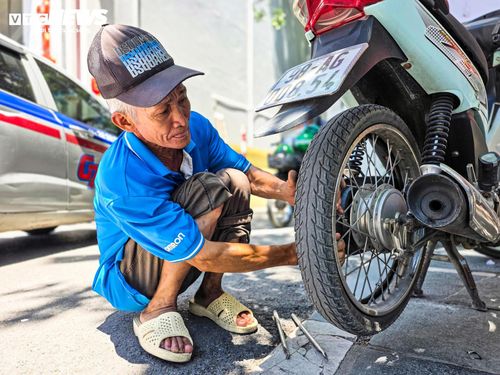 Trên vỉa hè đường Nguyễn Trãi, người thợ sửa xe vẫn miệt mài làm việc bên những chiếc xe của khách, bất chấp mặt đường hầm hập hơi nóng.