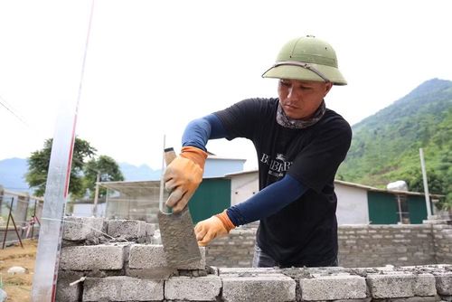 Công nhân tại dự án xây dựng Trường phổ thông nội trú liên cấp Tiểu học và Trung học cơ sở Minh Tân miệt mài làm việc dưới nắng hè oi bức.