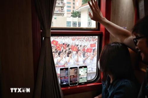 Qua ô cửa đoàn tàu, các cán bộ, nhân viên y tế Bệnh viện Bạch Mai vẫy chào đồng nghiệp trên chuyến tàu chuyên dụng Hà Nội-Phủ Lý trong ngày đầu vận hành. (Ảnh: Phạm Tuấn Anh/TTXVN)