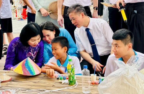 Các đại biểu cùng các em thiếu nhi trải nghiệm làm nón lá tại xã Dân Hòa. Ảnh: Bảo Lâm