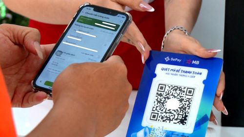 Người dân sử dụng điện thoại thông minh để thanh toán không dùng tiền mặt khi tiêu dùng. Ảnh: TRỌNG HIẾU