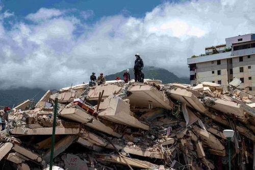 Lực lượng tìm kiếm cứu nạn và tình nguyện viên Venezuela tìm kiếm nạn nhân tại khu vực một tòa nhà bị sập ở thị trấn Caraballeda, bang La Guaira. Ảnh: Reuters