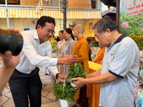 Người dân dự buổi ra mắt mô hình "Cơ sở tôn giáo xanh" nhận cây xanh do cán bộ trao tặng.