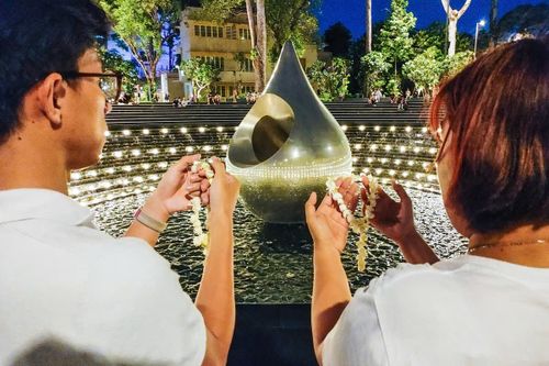 Du khách Quốc Thái (bìa trái) thực hiện nghi thức cầu bình an với vòng hoa lài tại Công viên Giọt nước.