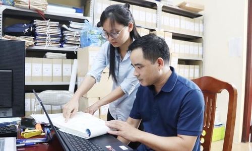 Cán bộ Phòng Kinh tế, Hạ tầng và Đô thị phường Nhân Hòa tra cứu dữ liệu đất đai với sổ lưu trữ.