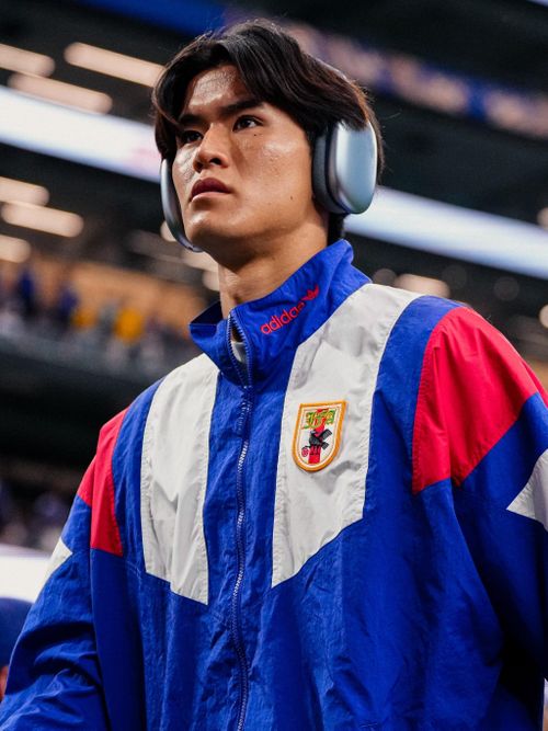 Nhật Bản tiếp tục khẳng định gu thẩm mỹ với bộ tracksuit mang đậm cảm hứng hoài cổ tại World Cup 2026. Thiết kế nổi bật nhờ những mảng màu tương phản, phom dáng vuông vức và chất liệu bóng, gợi nhớ các bộ đồ thể thao thập niên 1980 từng được giới sưu tầm đồ vintage săn đón. Điểm nhấn nằm ở huy hiệu trước ngực, mang dáng dấp biểu tượng quý tộc châu Âu hơn là logo thể thao hiện đại, tạo nên sự kết hợp hài hòa giữa nét cổ điển và bản sắc Nhật Bản.