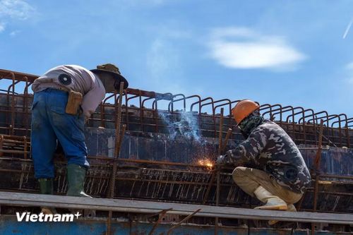 Những người thợ hàn cheo leo trên cao, bám sát các khung sắt để hàn nối kết cấu thép vững chắc cho trụ cầu vượt. (Ảnh: Thanh Phong/Vietnam+)