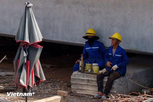 Phút nghỉ ngơi hiếm hoi của các công nhân. Họ tranh thủ ngả lưng, tránh nắng ngay dưới bóng râm của những bệ mố trụ cầu vừa hoàn thành. (Ảnh: Thanh Phong/Vietnam+)