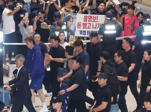 Ông Hong Myung Bo đi ngang qua một tấm biển phản đối tại Sân bay Quốc tế Incheon sáng 30/6. Ảnh: Korea Times