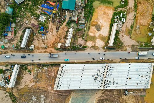 Các cấu kiện cầu, mặt bằng thi công và dòng phương tiện lưu thông nằm đan xen trên công trường.