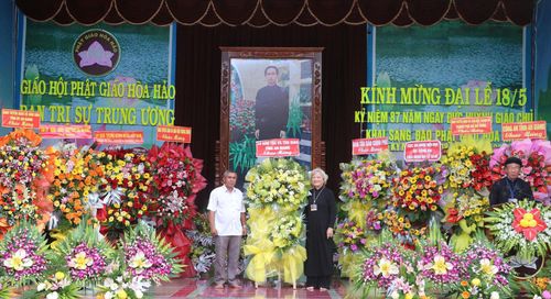 Ông Danh Lắm, Phó Giám đốc Sở Dân tộc và Tôn giáo tỉnh An Giang (trái) tặng hoa, chúc mừng Đại lễ kỷ niệm 87 năm Ngày khai sáng đạo Phật giáo Hòa Hảo
