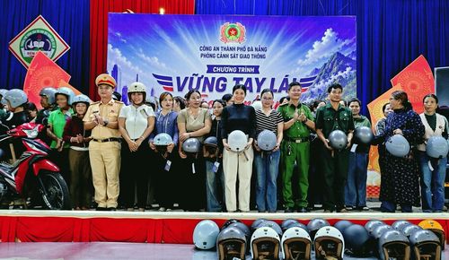 Lãnh đạo Công an xã Bến Giằng và Đội CSGT đường bộ số 3 tặng mũ bảo hiểm cho người dân.