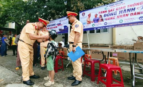 Một em nhỏ đi cùng mẹ đến tham gia chương trình “Vững tay lái - Trọn bình an” tỏ ra rất thích thú khi được lãnh đạo Phòng CSGT Công an TP Đà Nẵng hướng dẫn đội mũ bảo hiểm đúng cách và các kiến thức về an toàn giao thông.