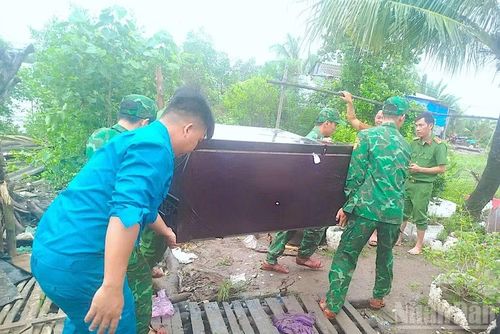 Cán bộ, chiến sĩ Đồn Biên phòng Đất Mũi giúp người dân di dời các dụng cụ trong nhà sau vụ sạt lở đất.