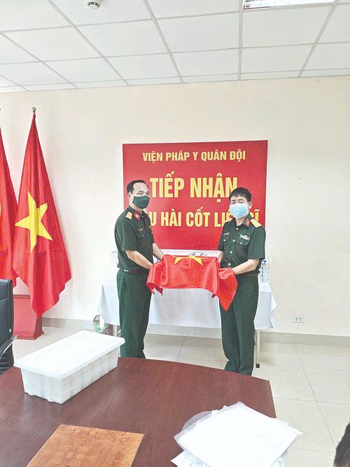 Đại diện Bộ Chỉ huy Quân sự tỉnh Lai Châu (bên phải) bàn giao mẫu hài cốt liệt sĩ chưa xác định được danh tính cho Viện Pháp y Quân đội (Cục Quân y, Bộ Quốc phòng) thực hiện giám định ADN.