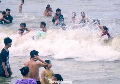 Nước đục, từng đợt sóng lớn ập vào, song du khách vẫn thích thú tắm biển.