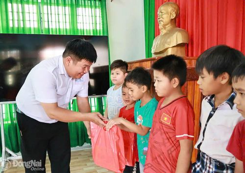 Đại diện sinh viên tình nguyện Mùa hè xanh Trường đại học Đồng Nai tặng quà cho trẻ em ở xã Đăk Ơ.