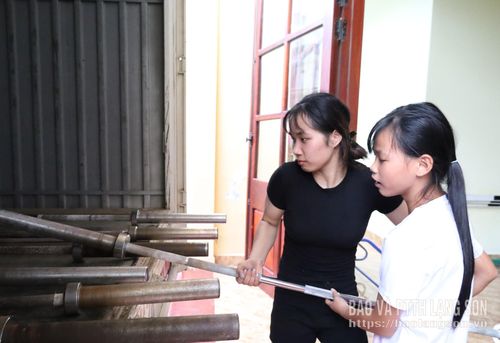 Các VĐV hỗ trợ vận chuyển thanh đòn tạ vào khu vực thi đấu