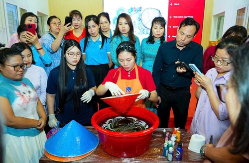 Các học viên trải nghiệm phương pháp “thủy ấn” trong sản xuất nón lá. Ảnh: PV