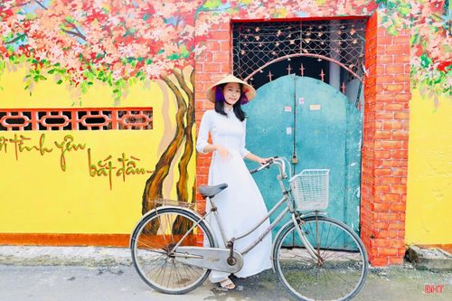 Trong tà áo dài truyền thống, nhiều bạn trẻ lựa chọn lưu lại những khoảnh khắc bên các bức bích họa rực rỡ sắc màu. Sự kết hợp giữa vẻ đẹp dịu dàng của tà áo dài với không gian nghệ thuật mang đậm hơi thở làng biển tạo nên những khung hình vừa hiện đại, vừa đậm bản sắc quê hương.