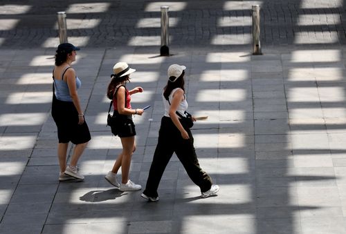 Người dân di chuyển trên đường phố dưới trời nắng nóng tại Seville, Tây Ban Nha. Ảnh: THX/TTXVN