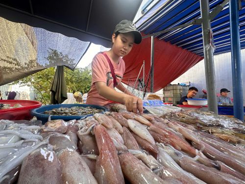 Đàm Ngọc Kim Ngân bên sạp cá của gia đình. Ảnh: HỮU TRUNG