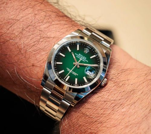 Trong hình ảnh, cha của Quang Dương đeo mẫu Datejust Ref. 126300-0026, kích thước 41 mm, nổi bật với mặt số xanh lá. Phần mặt số được phủ hoàn toàn bằng sơn mài lacquer, tạo hiệu ứng ombre chuyển từ xanh nhạt ở trung tâm sang sắc đậm hơn ở viền. Đây là lần đầu hãng Thụy Sĩ áp dụng kỹ thuật lacquer hoàn toàn cho mặt số ombre kể từ khi tái giới thiệu kiểu mặt số này vào năm 2019. Trên website của hãng, cỗ máy này có giá niêm yết hơn 260 triệu đồng.